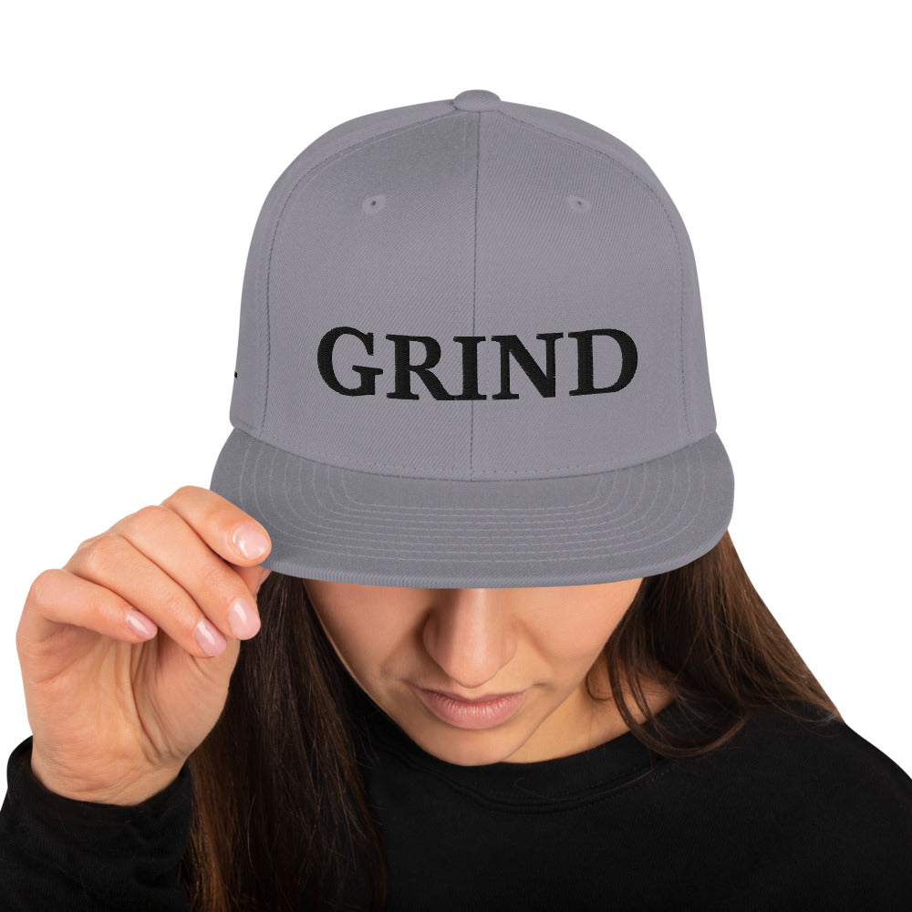 silver "grind" snapback hat with black letters 